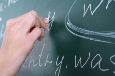 Female hand writing sentences on blackboard with chalk close up clipart