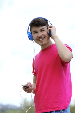 Adam mavi gökyüzü arka plan üzerinde kulaklık ile