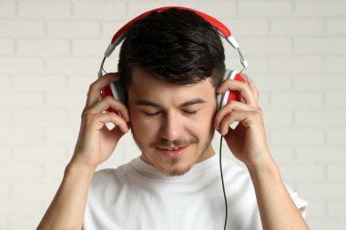 Yakışıklı genç adam tuğla duvar arka plan arka planda müzik dinlemek