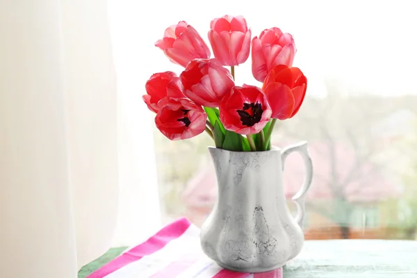 Beautiful bouquet of tulips in carafe on windowsill — Stock Photo, Image