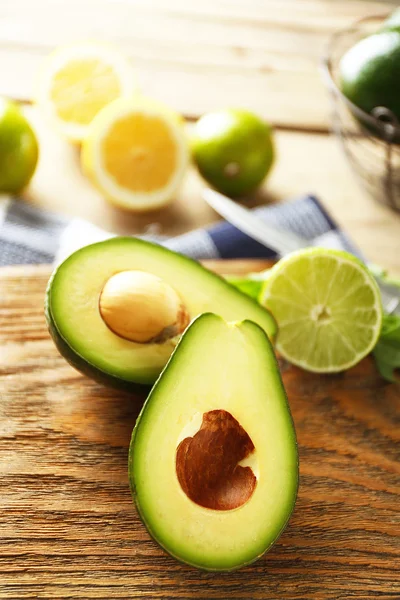 Sliced avocado and lemon lime on cutting board, on wooden background — Stock Photo, Image