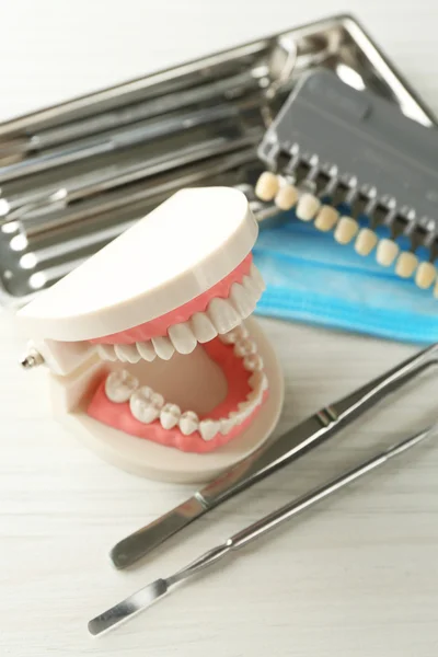 Weiße Zähne und zahnärztliche Instrumente auf Tischhintergrund — Stockfoto