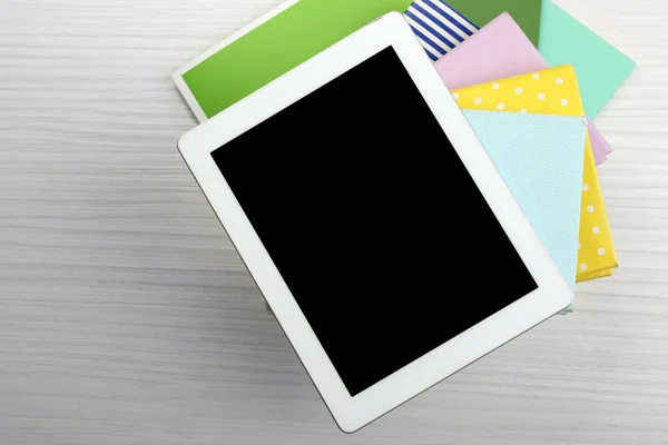 Notebook on top of pile of books and magazines on wooden background — Stock Photo, Image