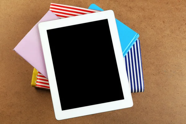 Notebook on top of pile of books and magazines on wooden background — Stock Photo, Image