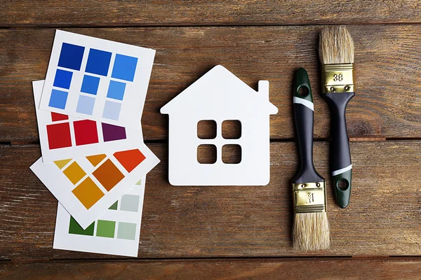 Échantillons de peinture colorés, maison décorative et pinceaux sur fond de table en bois — Photo