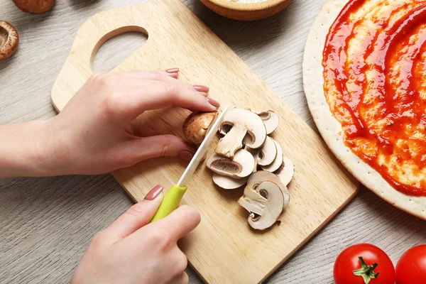 Руки женщины готовят пиццу на деревянном столе, крупный план — стоковое фото