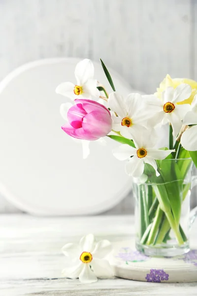 Bouquet primavera in tazza di vetro su sfondo di legno colore — Foto Stock