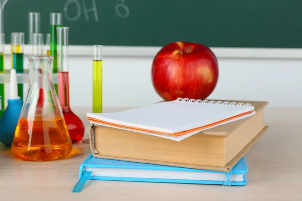 Schreibtisch im Chemieunterricht mit Reagenzgläsern auf grünem Tafel-Hintergrund — Stockfoto