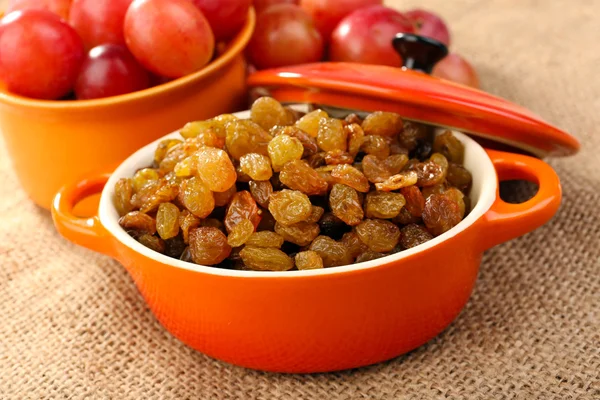 Raisins in bowl with grapes on table close up — Stock Photo, Image