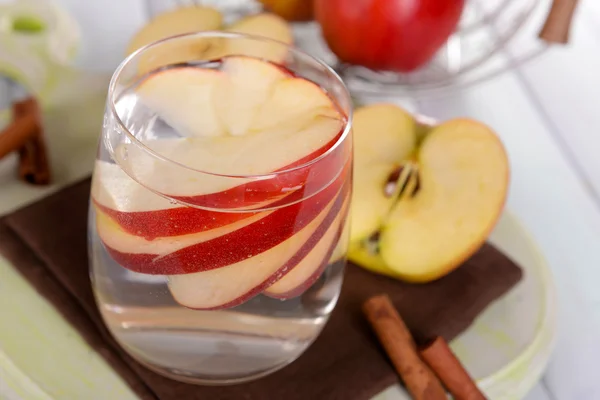 Glass of apple cider with fruits and cinnamon on table close up — Stock Photo, Image