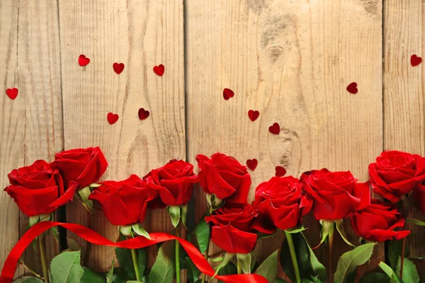 Beautiful red roses on old wooden table — Stock Photo, Image