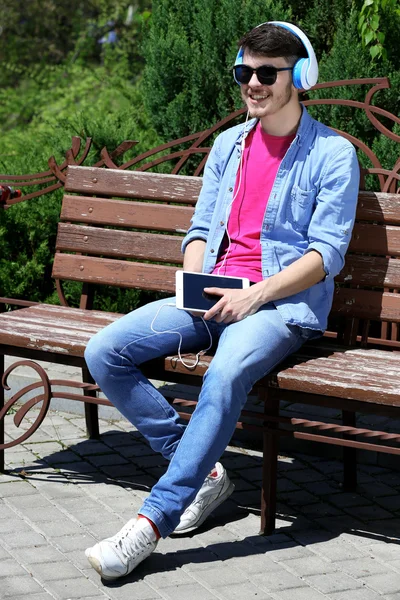 Man with headphones resting on bench in park — Stock Photo, Image