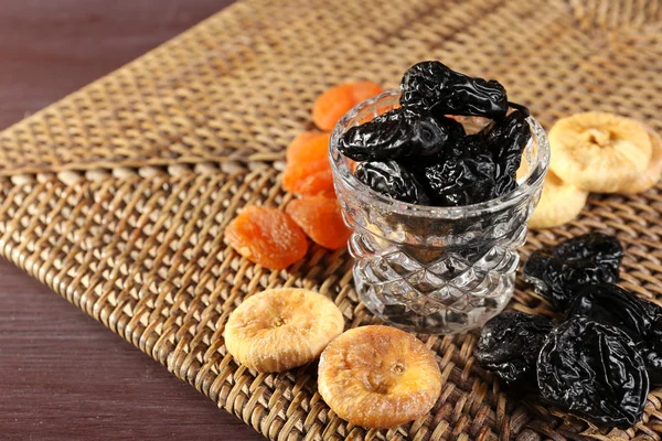 Prunes and other dried fruits on wicker mat, closeup — Stock Photo, Image