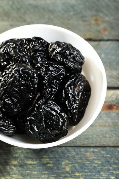 Saucer of prunes on wooden table, closeup — Stock Photo, Image