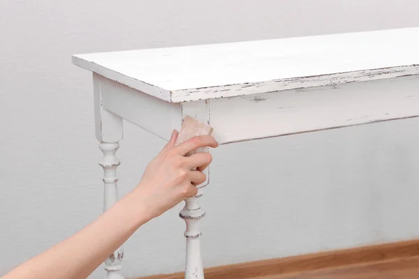 Mano femenina quitando pintura de mesa de madera para la decoración, en interiores —  Fotos de Stock