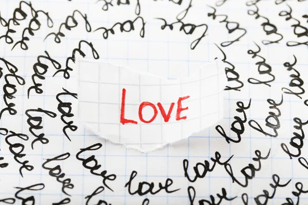 Word LOVE written on torn paper on sheet of paper background — Stock Photo, Image