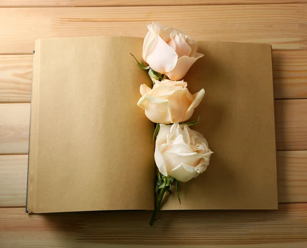 Rosas frescas en cuaderno viejo, sobre fondo de mesa de madera —  Fotos de Stock