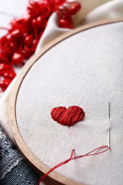 Le cerceau de broderie avec toile et fils à coudre rouges sur la table close up — Photo