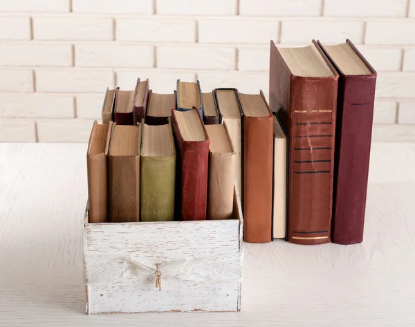 Tumpukan buku-buku tua di dinding bata latar belakang — Stok Foto