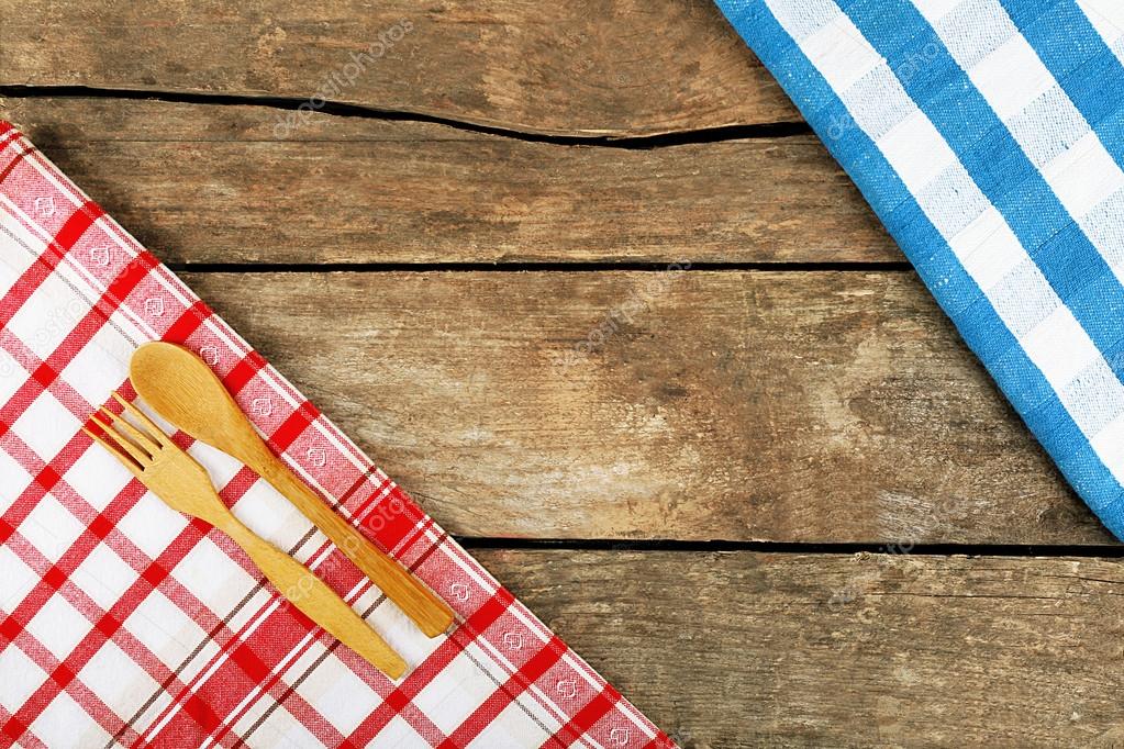 Checkered napkin with fork and spoon on wooden table background