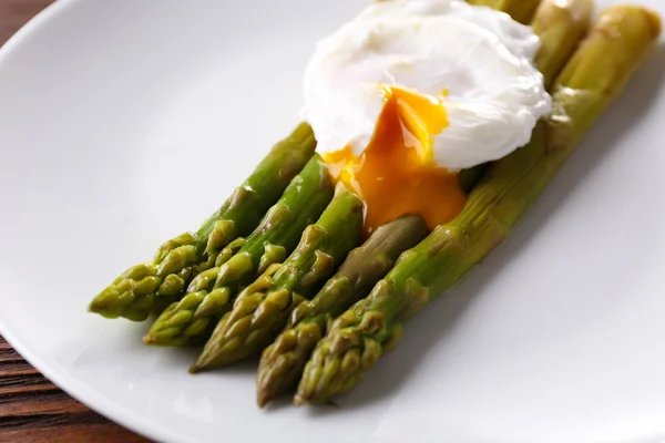 Roasted asparagus with poached egg on plate on table close up — Stock Photo, Image