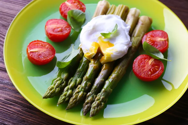 Gebratener Spargel mit Tomaten und pochiertem Ei auf Teller auf dem Tisch aus nächster Nähe — Stockfoto