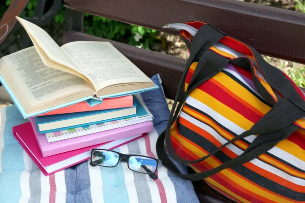 Libri, bicchieri e borsa su panca all'aperto — Foto Stock