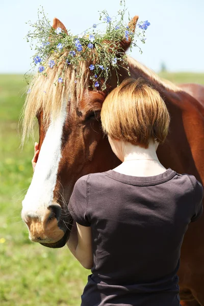 Portrait of beautiful brown horse with wreath and young woman, outdoors — Stock Photo, Image