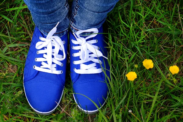 Vrouwelijke voeten in gumshoes op groen gras achtergrond — Stockfoto