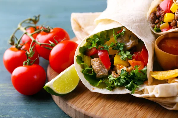 Burrito saboroso caseiro com legumes, batatas fritas na placa de corte, no fundo de madeira — Fotografia de Stock