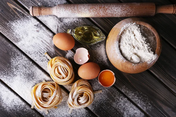 Сырая домашняя паста и ингредиенты для макарон на деревянном фоне — стоковое фото