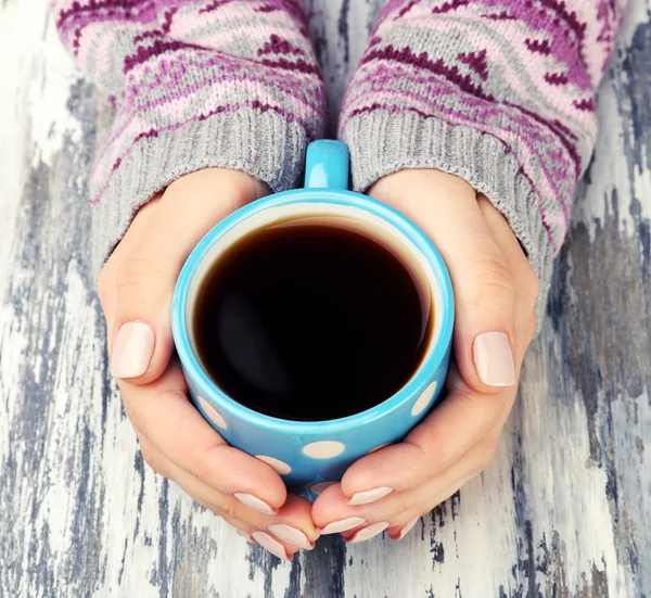 Female hands holding cup of coffee on wooden background — Stock Photo, Image