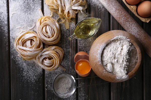 Raw homemade pasta and ingredients for pasta on wooden background — Stock Photo, Image