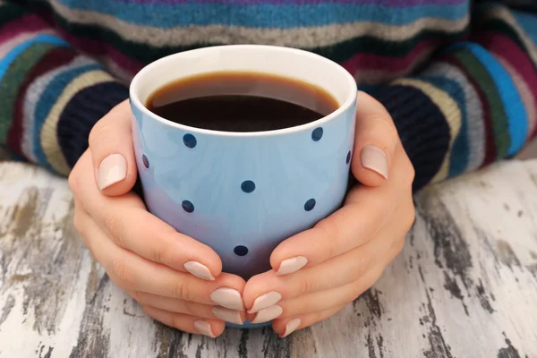 木製テーブルの上のコーヒー カップを保持している女性の手をクローズ アップ — ストック写真