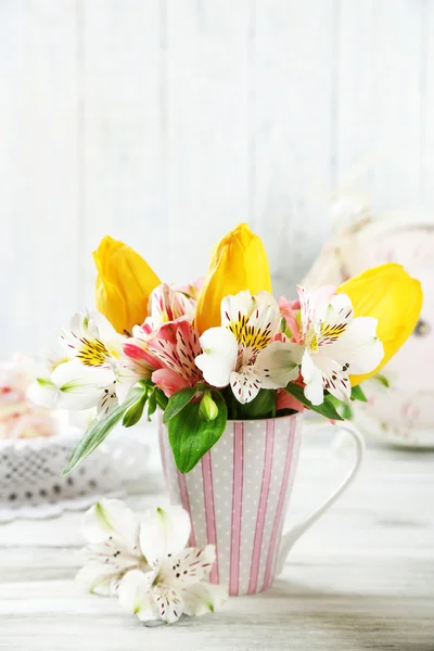 Mooie bloemen in cup, op houten achtergrond — Stockfoto