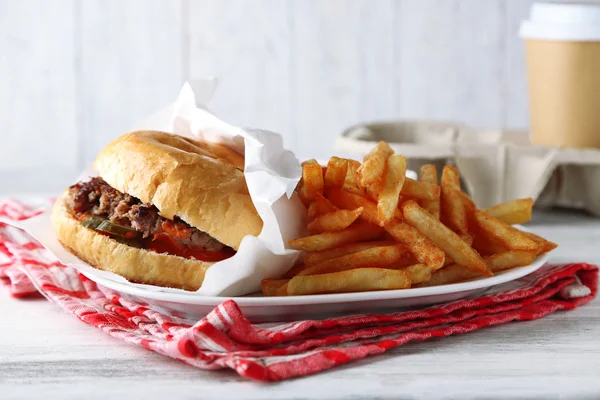 Lezzetli hamburger ve patates kızartması tabakta, ahşap masa arkasında. Sağlıksız gıda konsepti — Stok fotoğraf