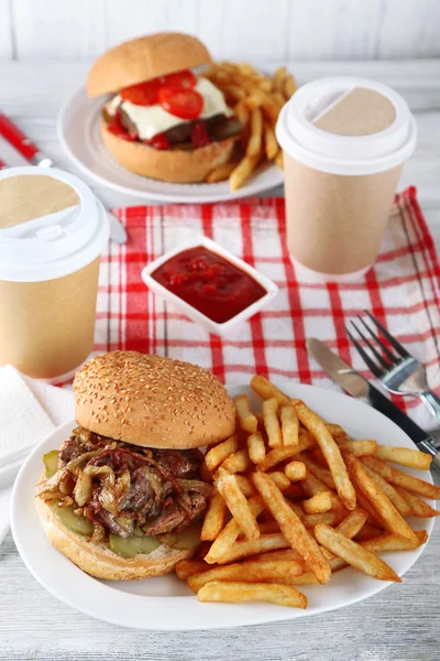 Leckere Burger und Pommes auf Teller, auf Holztischhintergrund. Ungesundes Ernährungskonzept — Stockfoto