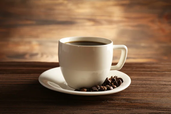 Cup of coffee with grains on wooden background — Stock Photo, Image