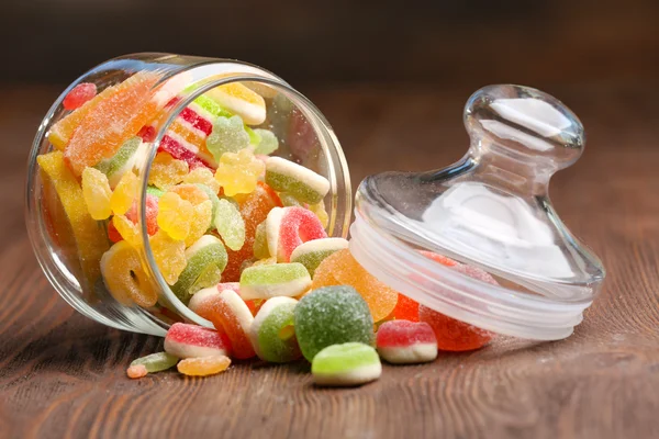 Kolorowe cukierki w słoiku na stole na drewniane tła — Zdjęcie stockowe