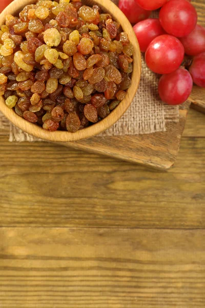 Raisins in bowl with grapes — Stock Photo, Image