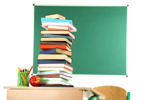 Trä skrivbord med böcker och stol i klass på blackboard bakgrund — Stockfoto