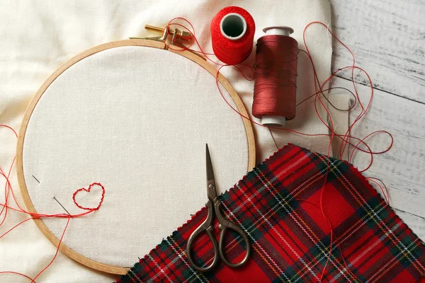 The embroidery hoop with canvas and red sewing threads on table close up — Stock Photo, Image