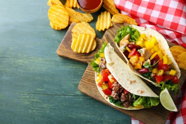 ahşap arka plan üzerinde kesme tahtası üzerinde ev yapımı sığır eti burrito sebzeli patates cips