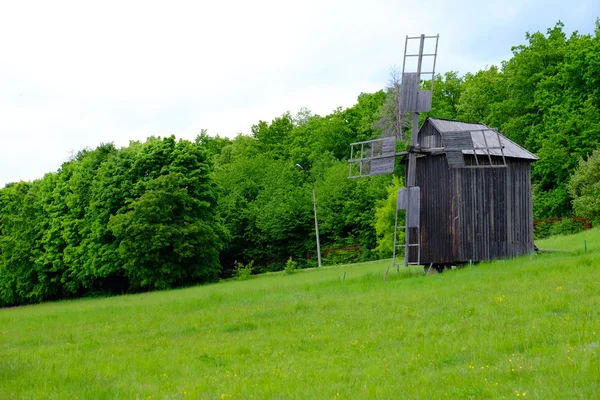 Oude houten windmolens op groen veld, op blauwe hemelachtergrond — Stockfoto