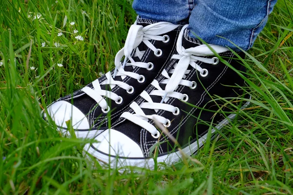 Piedi femminili in gomme su sfondo verde erba — Foto Stock