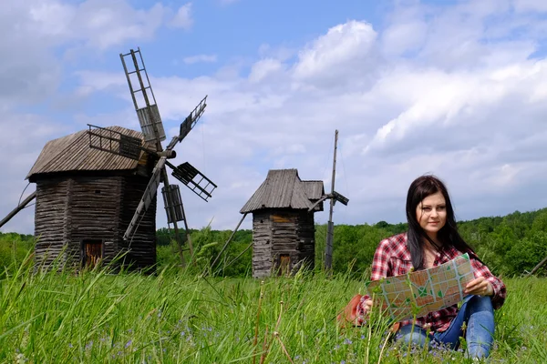 Young woman tourist with backpack and map on beautiful landscape background — Stock Photo, Image