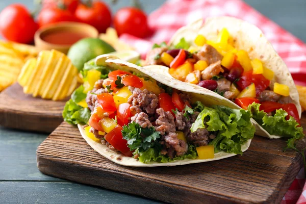 Domácí hovězí burritos s zeleninou, hranolky na prkénko, na dřevěné pozadí — Stock fotografie