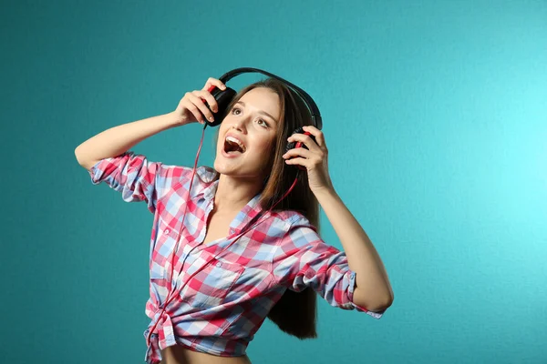 Young woman with headphones on turquoise background — Stock Photo, Image