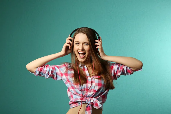 Young woman with headphones on turquoise background — Stock Photo, Image