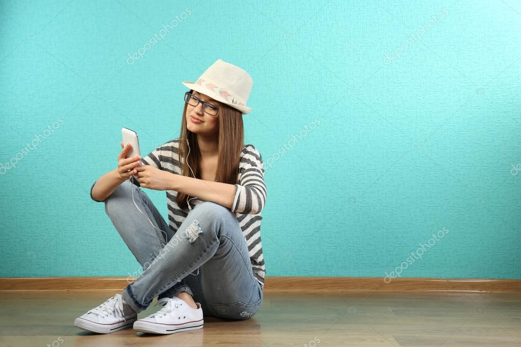 ターコイズ ブルーの壁紙の背景の上にヘッドフォンを床に座っていた若い女性 ストック写真 C Belchonock 74210921
